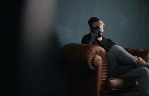 Image of a man sitting on the couch looking overwhelmed