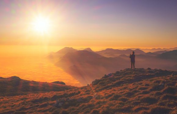 Person looking at a sunrise on a hills