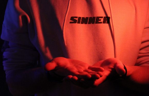 Person wearing a sweatshirt with the word sinner on the front