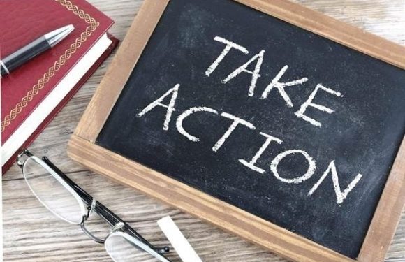 Chalkboard with words "Take action" next to reading glasses, a pen and a notebook.