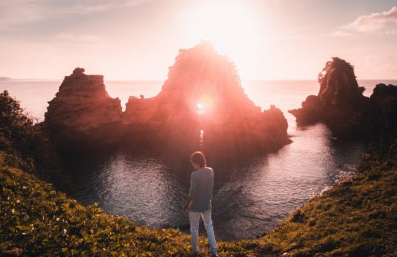 Person standing on the edge of a cliff with a light ahead of her