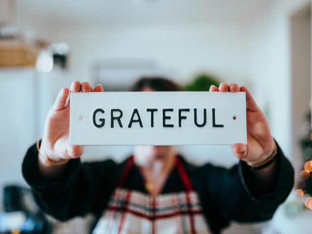 Hands holding up a sign that says "Grateful"