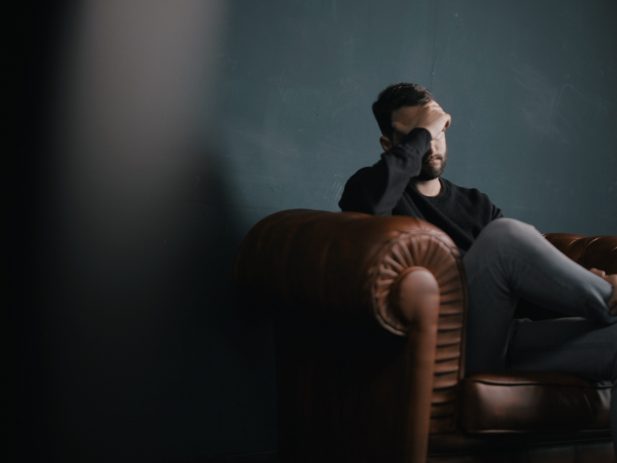 Image of a man sitting on the couch looking overwhelmed