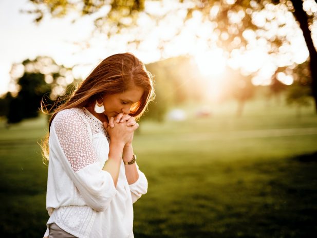 Woman in prayer in open sunlight area