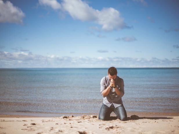 Man on the beach praying