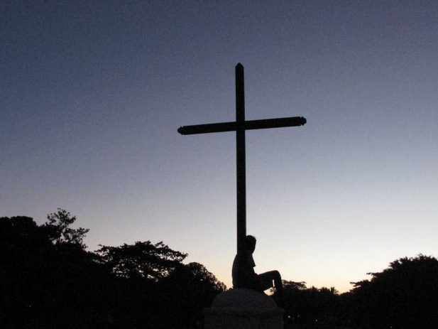 Cross with a person sitting at the foot of the cross