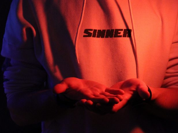 Person wearing a sweatshirt with the word sinner on the front