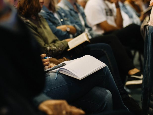 People attending church together, sitting in a row with bibles open.