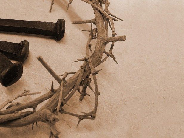 Close up photo of a crown of thorns with 3 black old nails