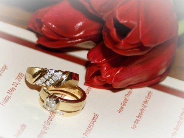 Wedding rings and red tulips on top of Wedding program