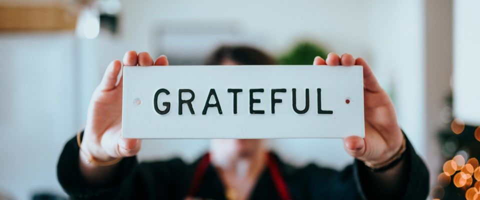 Hands holding up a sign that says "Grateful"