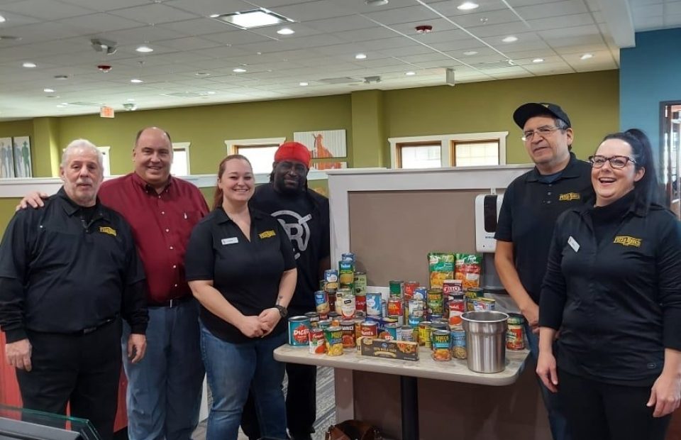 Gillette Wyoming Pizza Ranch team gathered around a table displaying their donations given at their soft-opening.