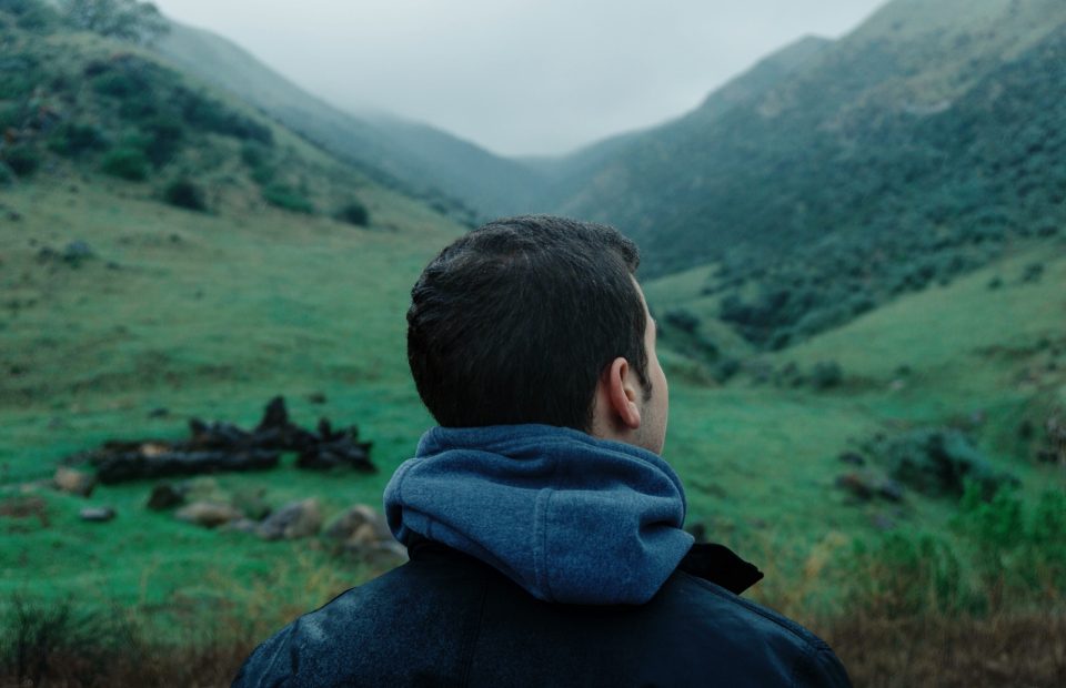 Man standing in a valley looking at which path he should take