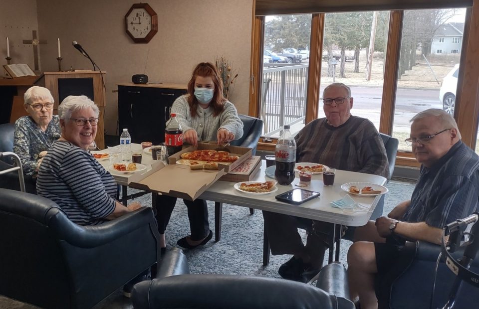 Group of people sitting around a table eating Pizza Ranch pizza