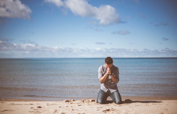 Man on beach praying