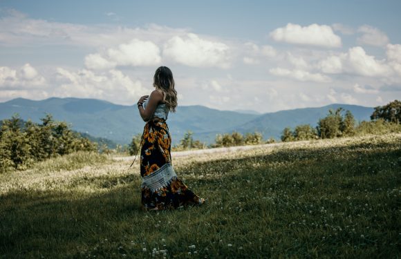 Woman looking over a prairie at sunset