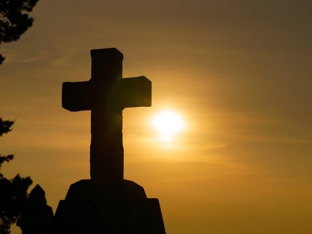 Cement Cross with Rising Sun in the background