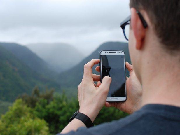 Person taking picture of mountains with cell phone